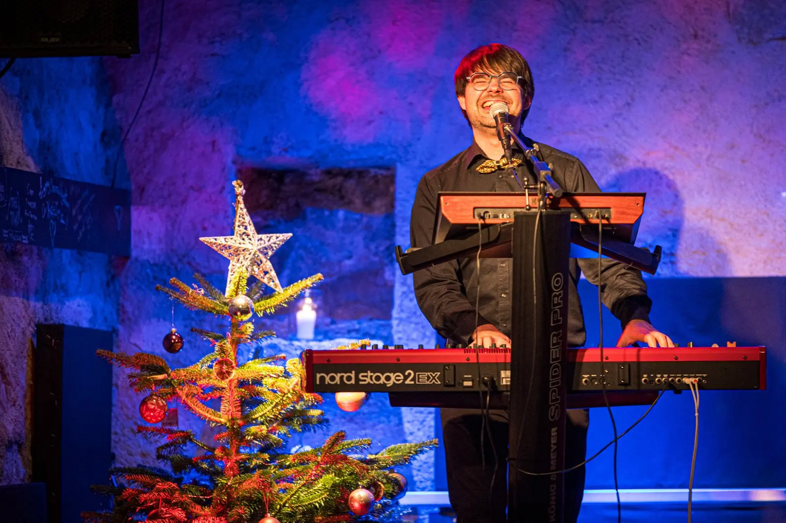 Tanguy au clavier, hilare, à côté d’un sapin de Noël