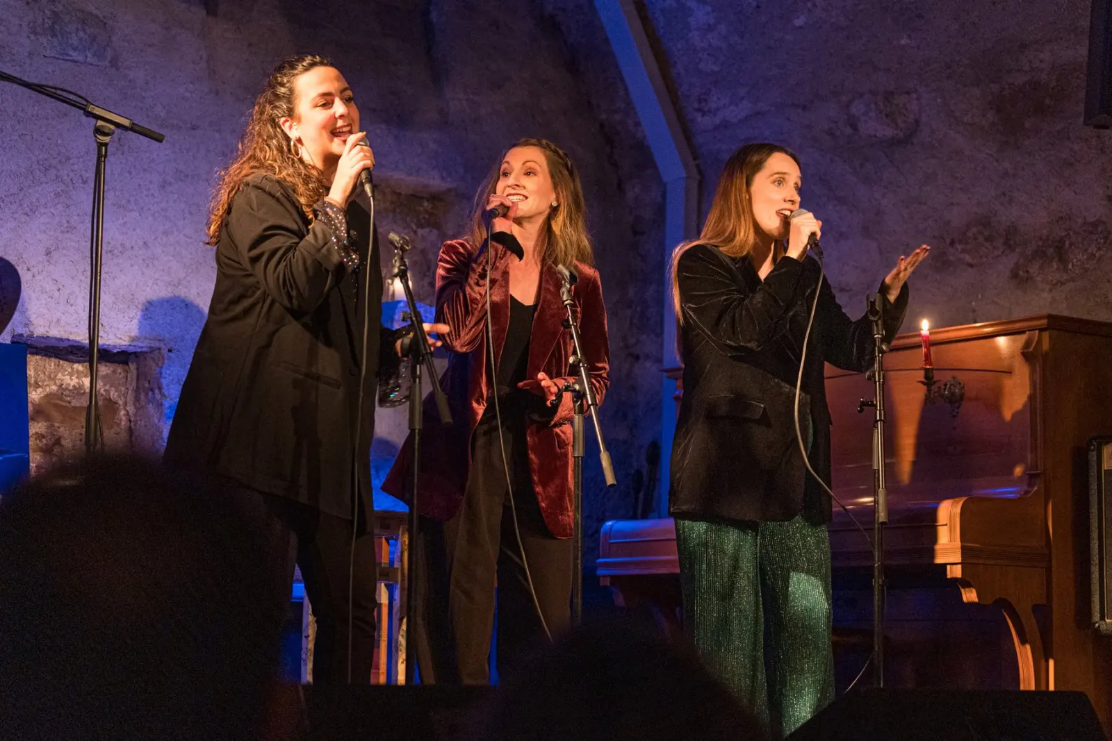 Les trois chanteuses du trio sur scène sous une lumière bleue, pendant un concert Winter is groovin’